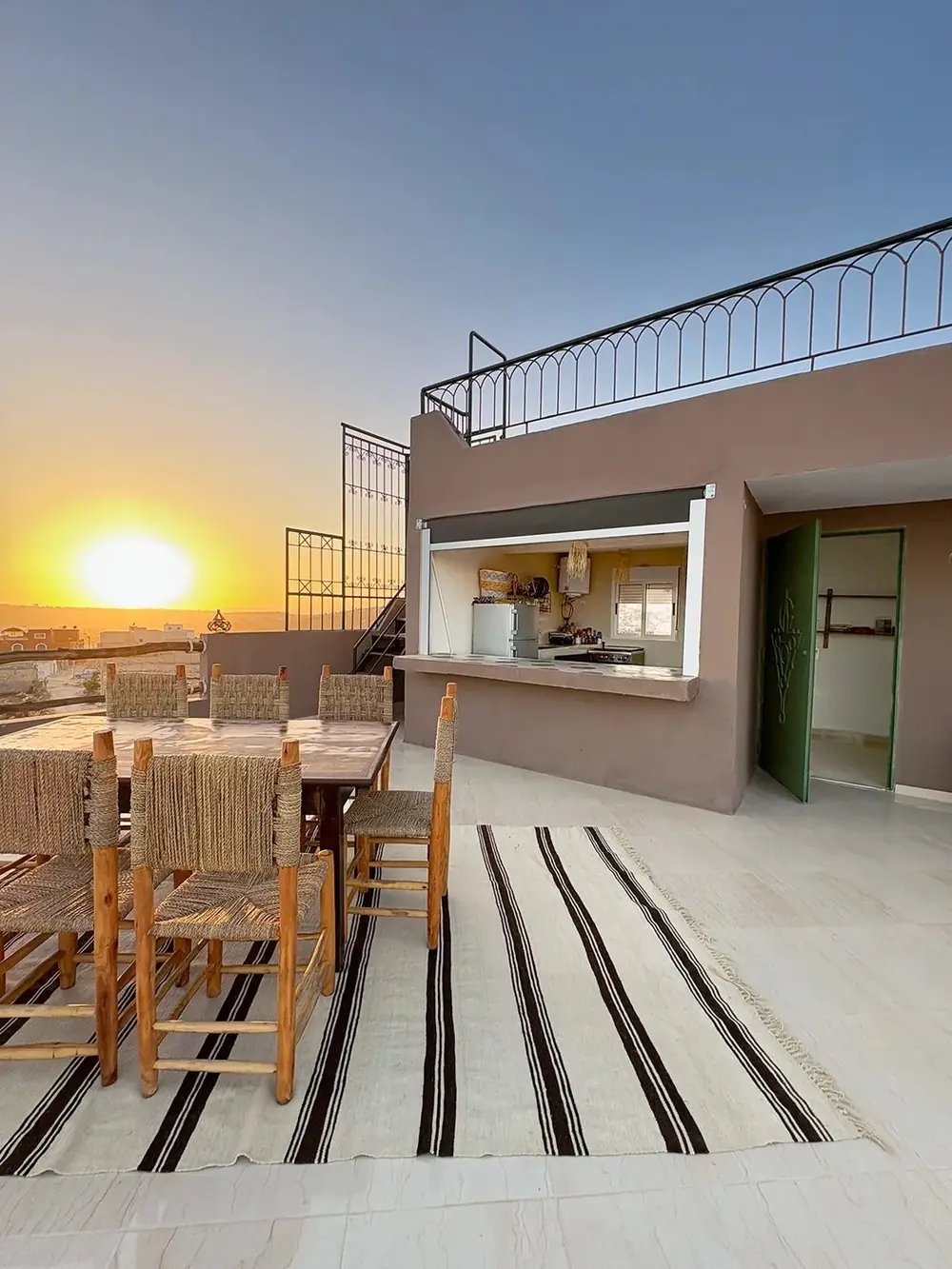 Rooftop dining table at sunset with the open kitchen behind